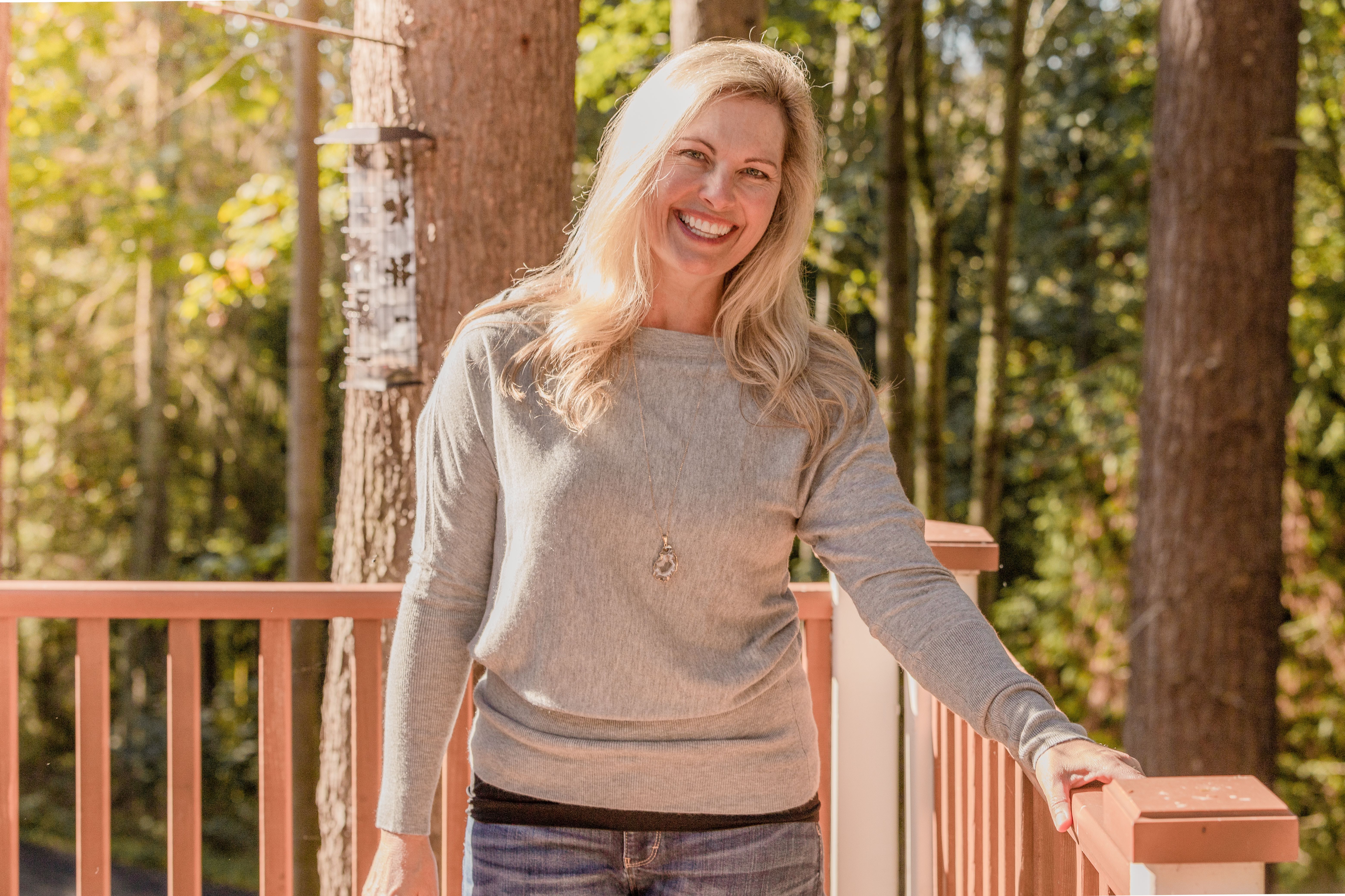 The image likely shows a woman standing in front of a wooden fence.