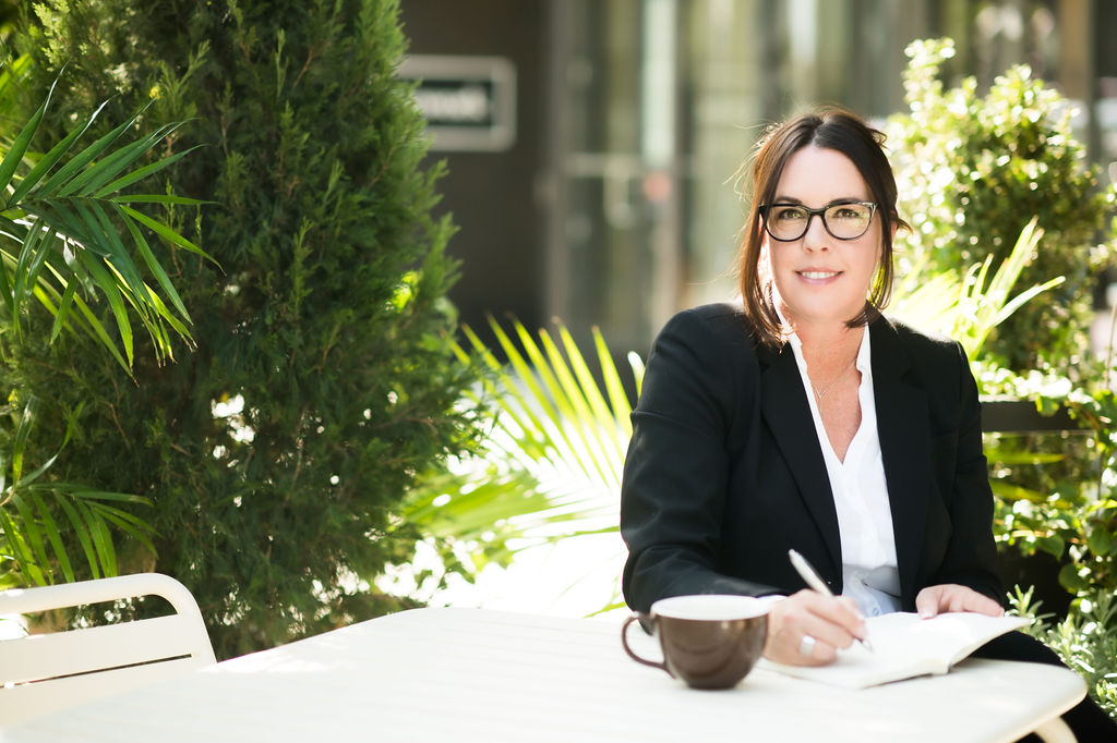 A woman sitting at a table with a cup of coffee