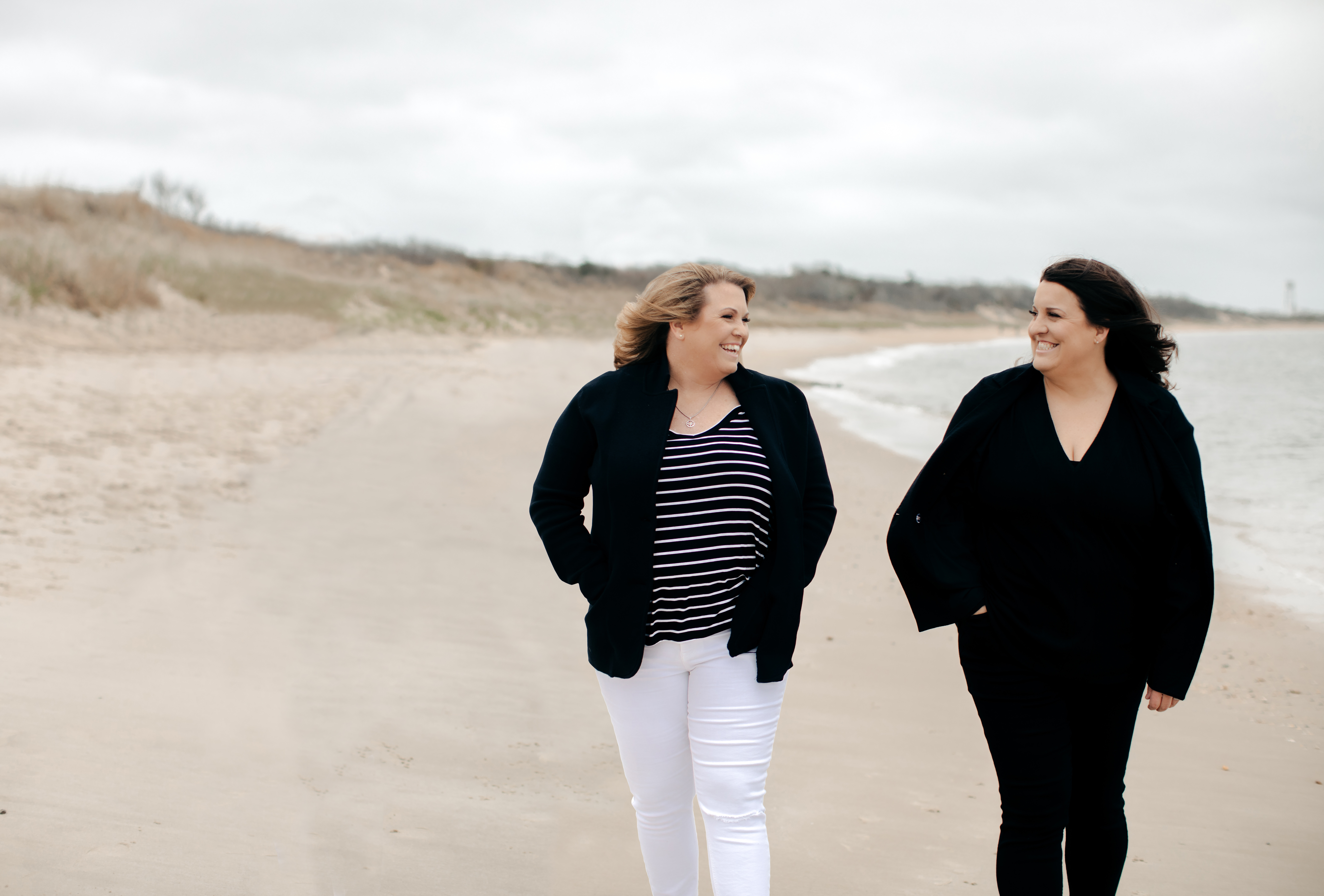Two women walking on a beach near the ocean