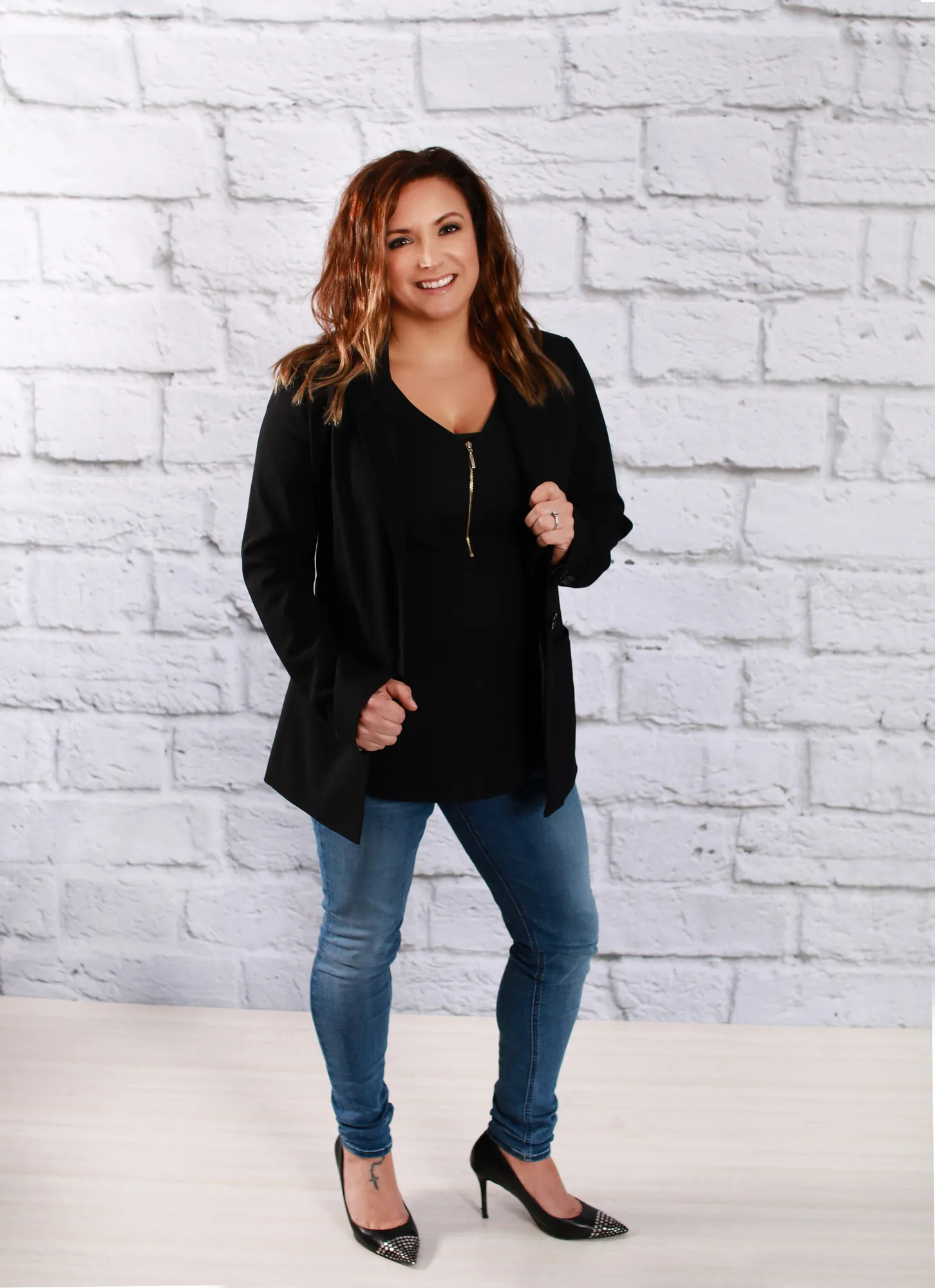 a woman standing on a brick wall with a cell phone