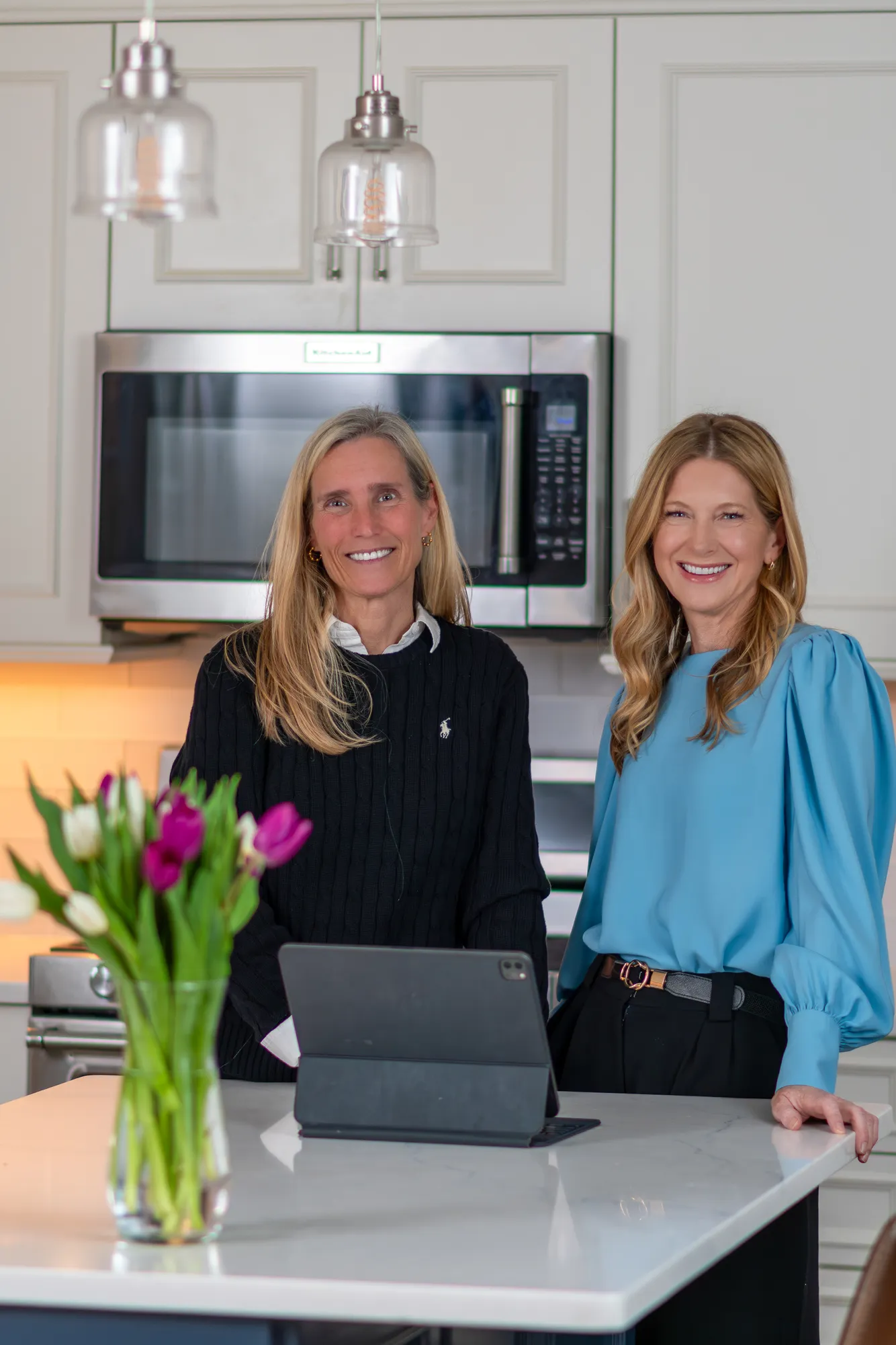 Jen Holden and Megan Koppe of The Jen Holden Group, Annapolis and Severna Park real estate agents, in a bright kitchen