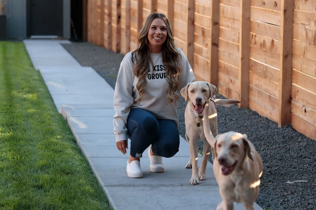 A woman sitting on the sidewalk with a dog and a group.