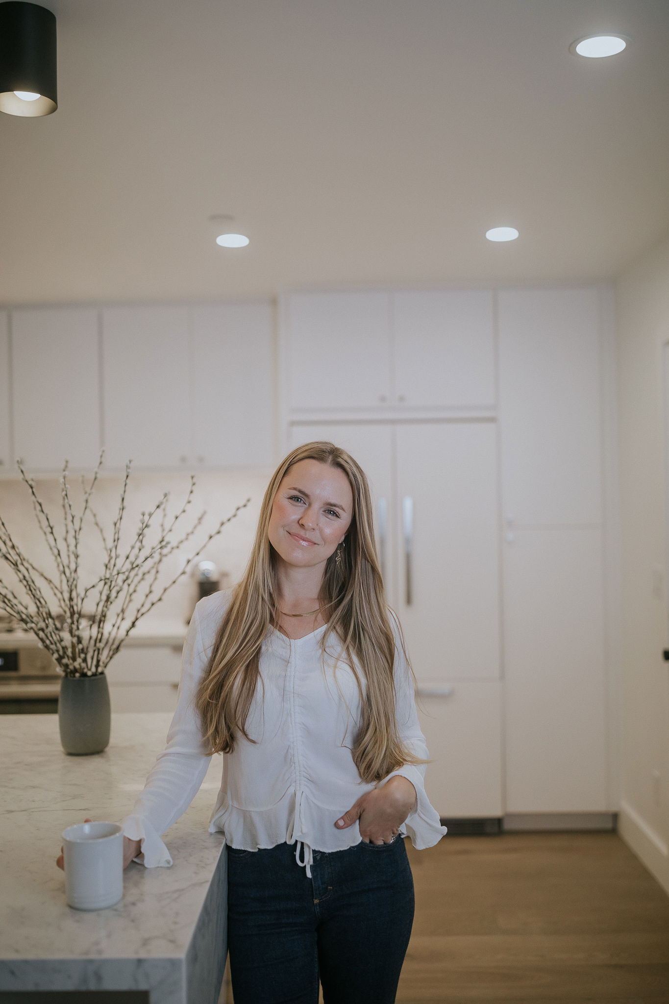 A woman standing in a kitchen with a white towel around her neck