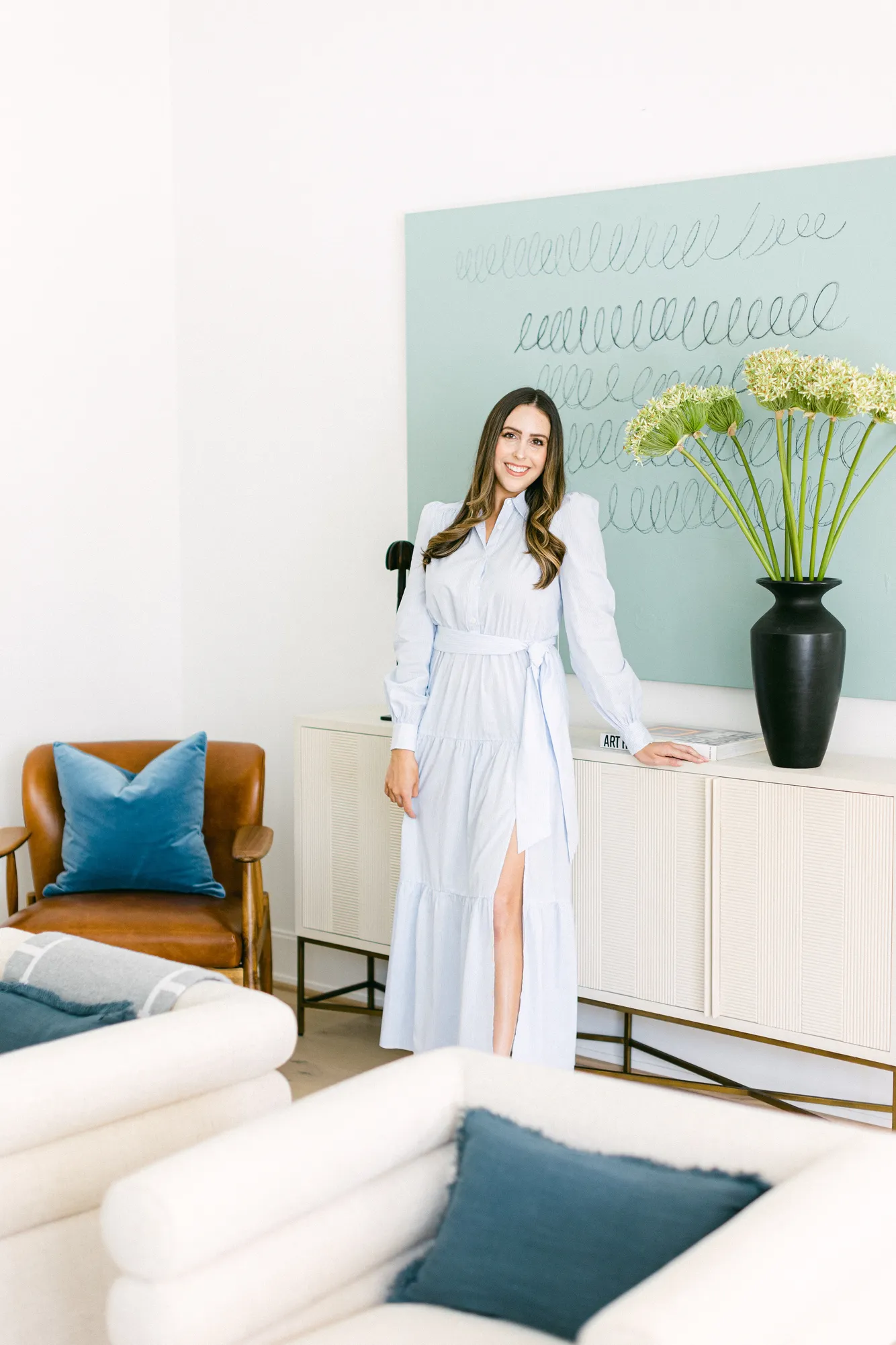 A woman standing in front of a wall with a painting