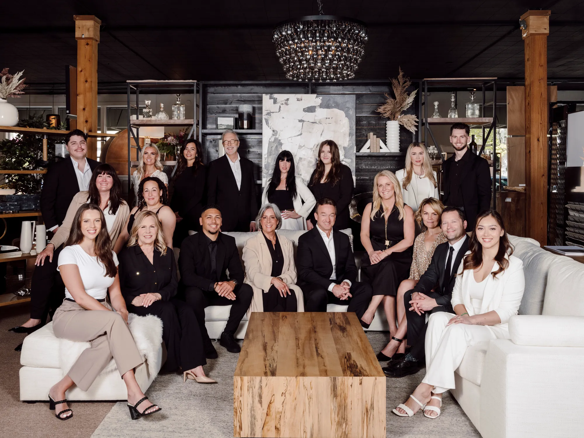 A group of people posed for a team photo, some seated and some standing, in a room with neutral-colored walls and decor.