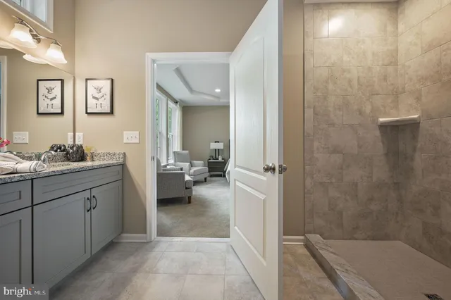 a en suite bathroom with a granite countertop sink a mirror and a bathtub
