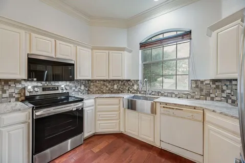a kitchen with cabinets stainless steel appliances a sink and wooden floor