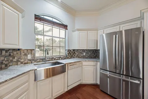 a kitchen with white cabinets sink and appliances