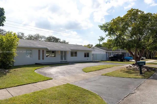 a front view of a house with a garden and trees