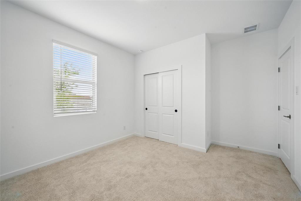 1413 Richardson Street Howe, TX 75459 - Photo 12 of 30 Neutral tone carpeted room featuring a window with blinds, white walls, and a closet with sliding doors