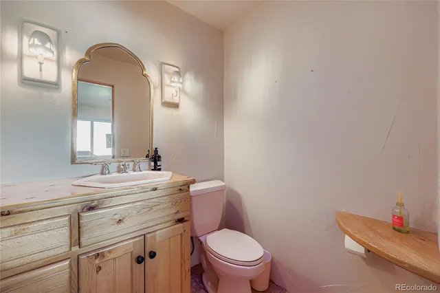 a bathroom with a toilet sink vanity and mirror
