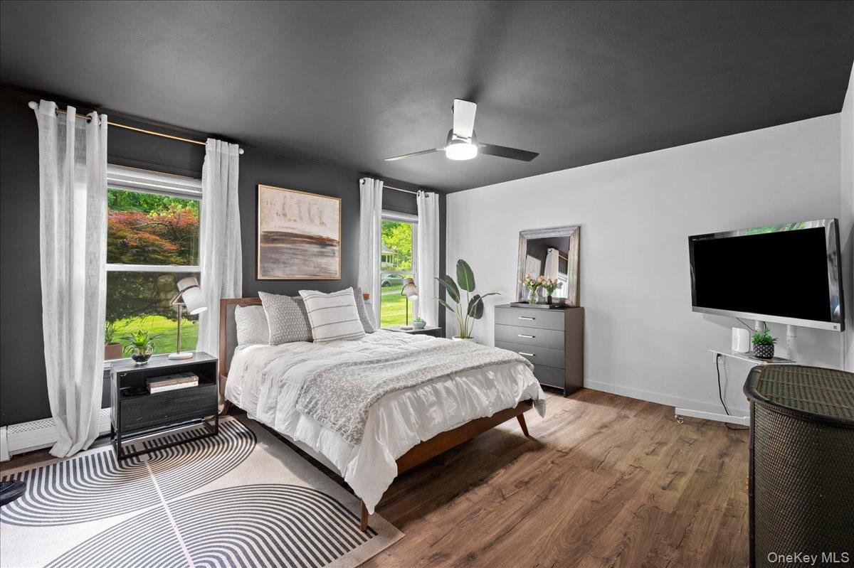 13 Jacks Pond Road Newburgh, NY 12550 - Photo 18 of 44 Bright and spacious main-floor bedroom with wood-finish flooring, two large windows, a ceiling fan with integrated lighting, and a calming neutral palette.
