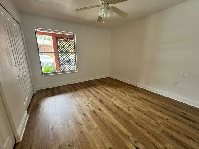 an empty room with wooden floor chandelier fan and windows