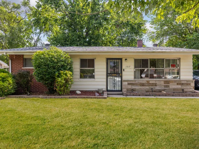 a front view of house with yard and trees in the background