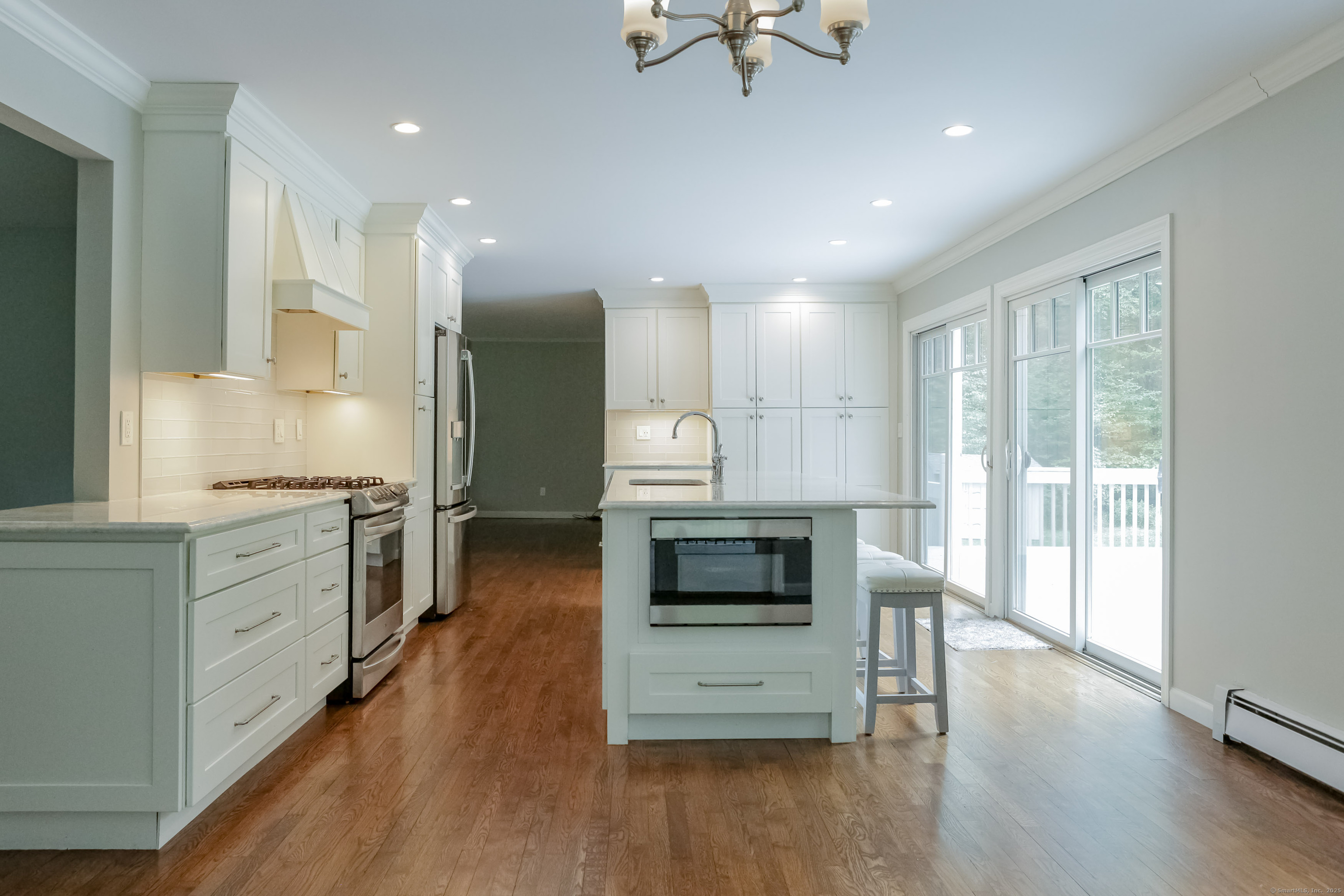 161 Foggwood Road Fairfield, CT 06824 - Photo 4 of 34 a kitchen with stainless steel appliances kitchen island granite countertop a stove a sink and white cabinets with wooden floor next to windows