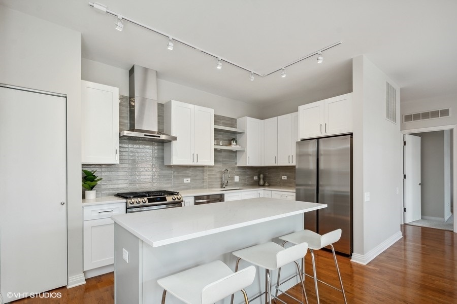 560 West Fulton Street, Unit 504 Chicago, IL 60661 - Photo 7 of 17 a kitchen with stainless steel appliances a refrigerator a stove a sink and white cabinets with wooden floor