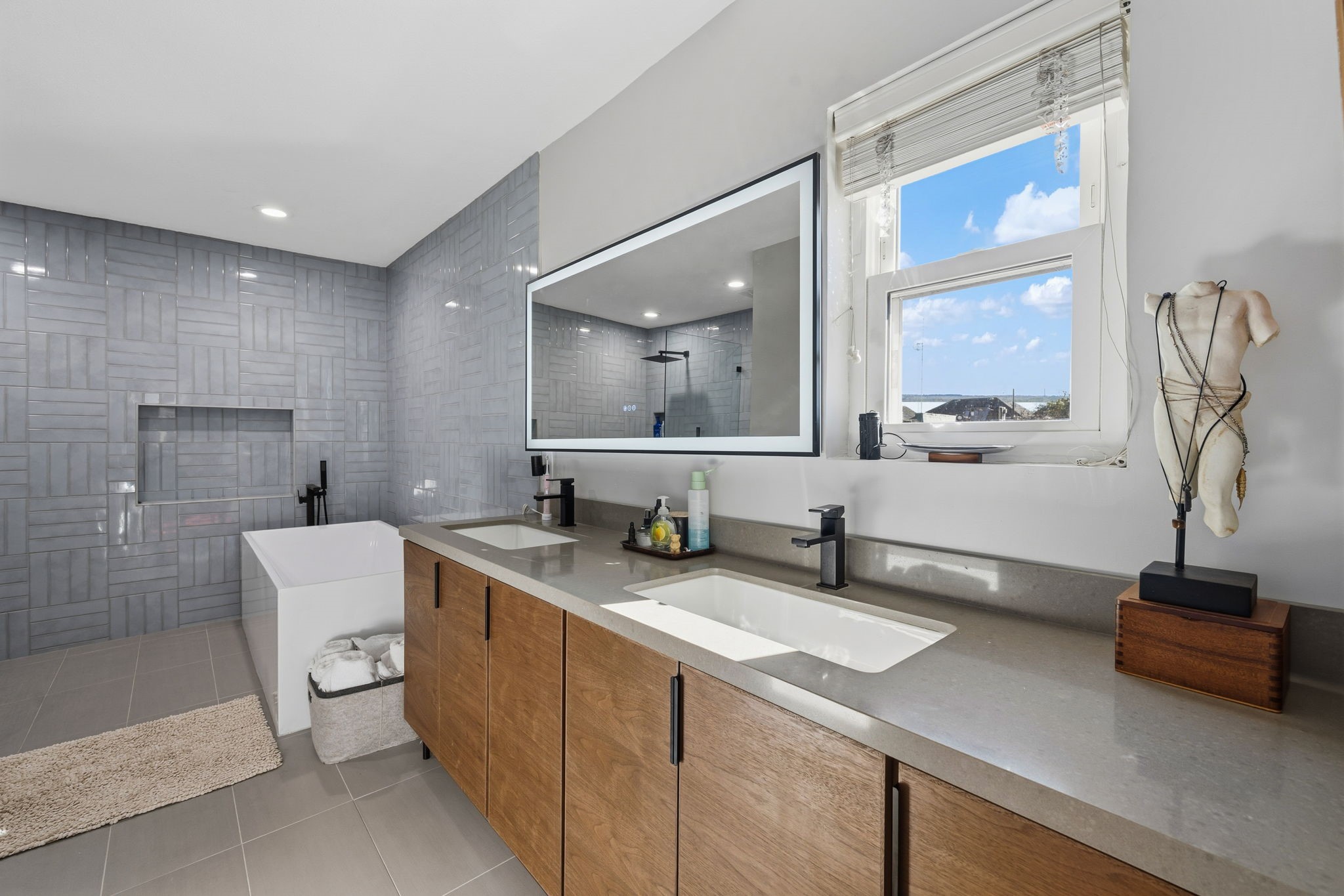 1831 Palm Street Houston, TX 77004 - Photo 15 of 27 Featuring a sleek double-sink floating vanity with ample storage, a large backlit mirror, and a window for natural light.