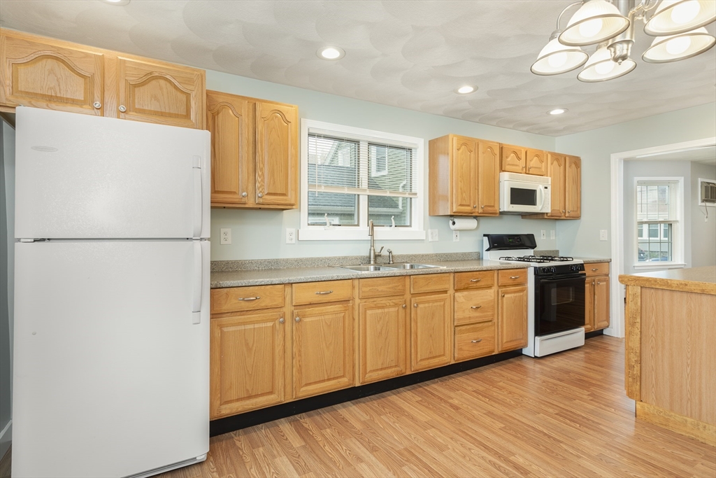 22 Clovelly Street Lynn, MA 01902 - Photo 8 of 28 a kitchen with granite countertop a refrigerator a sink dishwasher a stove top oven a dining table and chairs with wooden floor