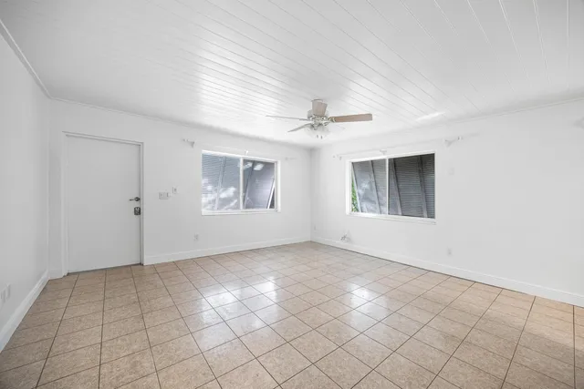 an empty room with windows and chandelier fan