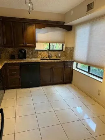 a kitchen with granite countertop a stove a sink a counter space and cabinets