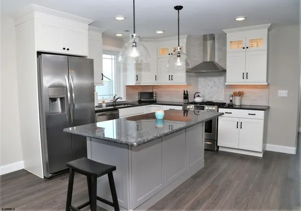 a kitchen with stainless steel appliances granite countertop a sink a stove and a refrigerator