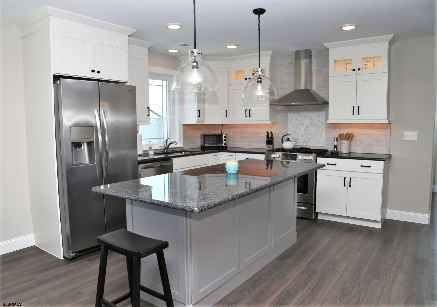 a kitchen with stainless steel appliances granite countertop a sink a stove and a refrigerator