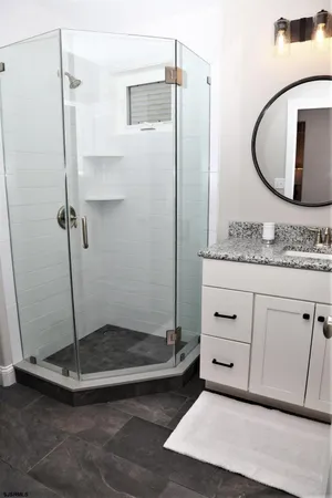 a bathroom with a granite countertop sink a mirror and a shower
