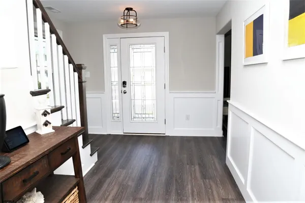 a view of a hallway to a livingroom with wooden floor and furniture