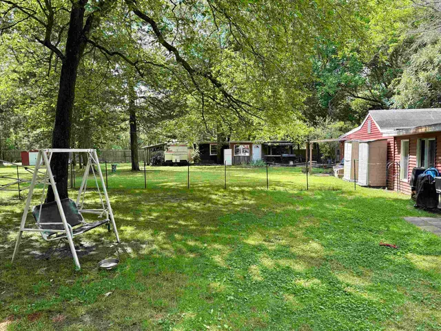 a view of house with a backyard and a garden