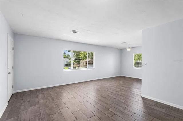 an empty room with wooden floor and windows