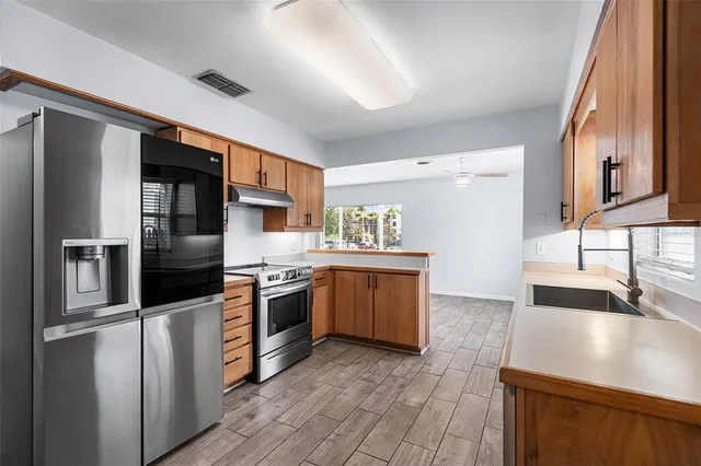 a kitchen with stainless steel appliances granite countertop a sink a stove and a wooden floors