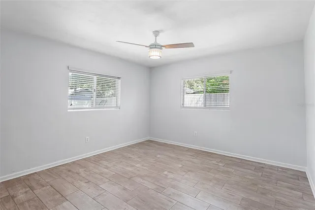 a view of an empty room with wooden floor and a window