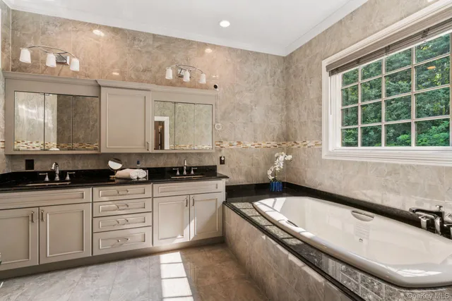 a large bathroom with a granite countertop tub a double vanity sink a window and a mirror