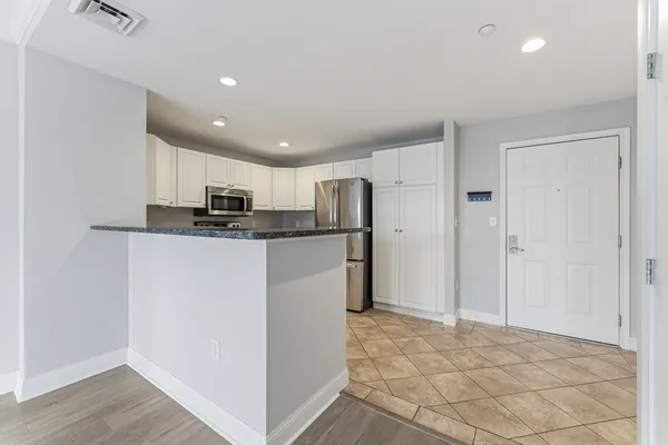 a kitchen with granite countertop a refrigerator and a stove top oven