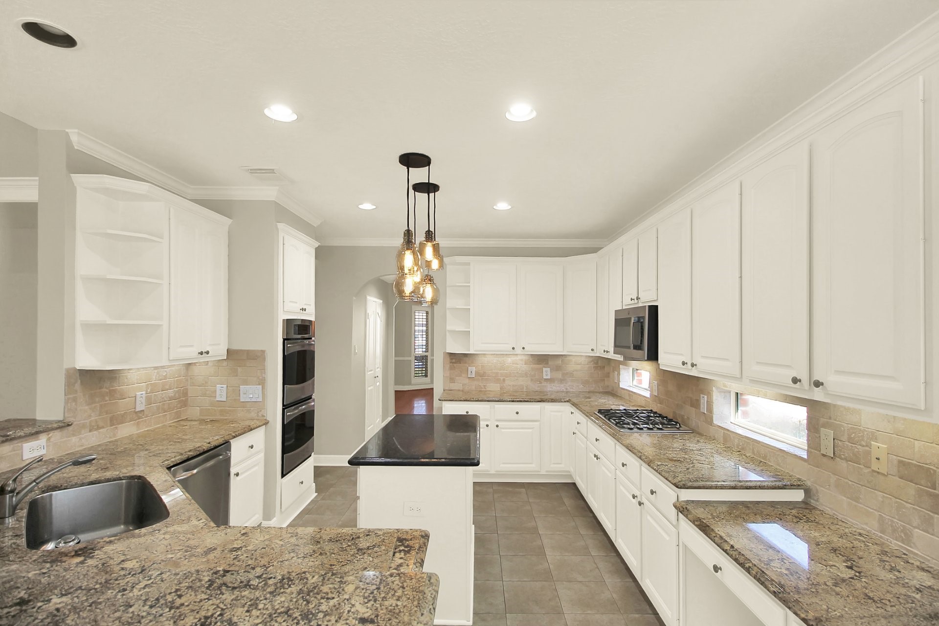 601 Forest Bend Lane Friendswood, TX 77546 - Photo 5 of 27 a large kitchen with stainless steel appliances kitchen island granite countertop a sink and a stove