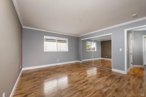a view of an empty room with window and wooden floor