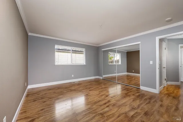 a view of an empty room with window and wooden floor