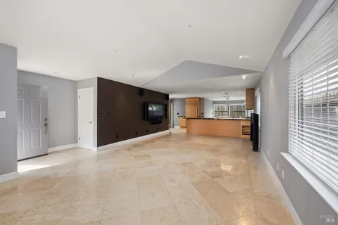 a view of empty room with kitchen and windows