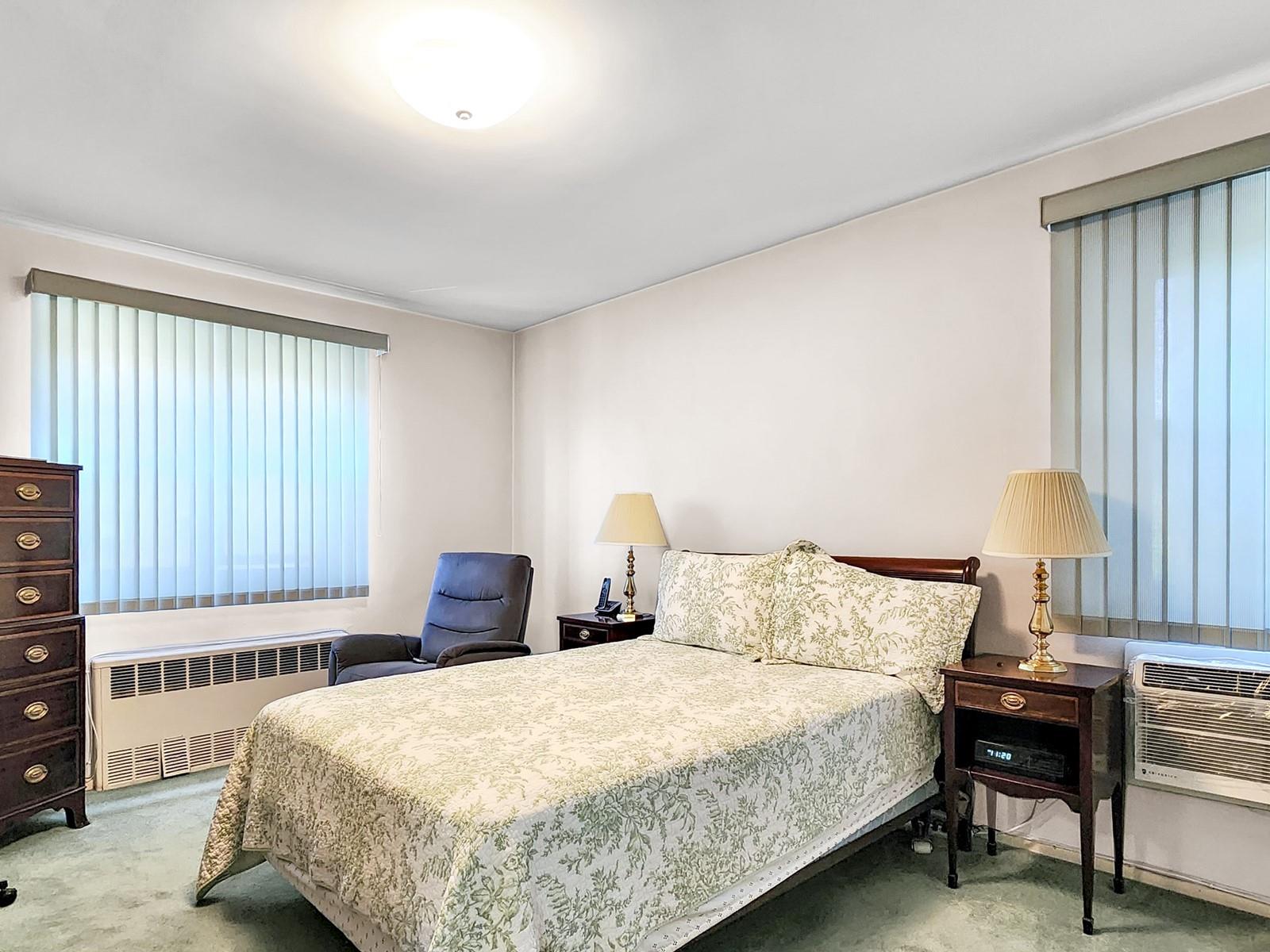 140-21 31st Road, Unit 4A Queens, NY 11354 - Photo 5 of 7 a bedroom with a bed a lamp and a large window