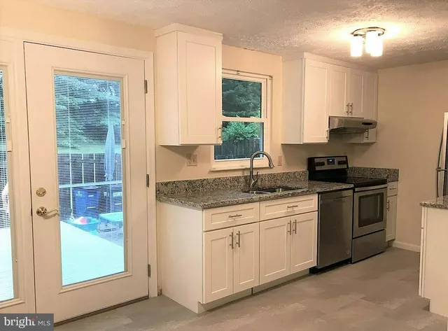 a kitchen with stainless steel appliances granite countertop a stove a sink and a refrigerator