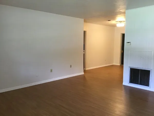 an empty room with wooden floor and fireplace