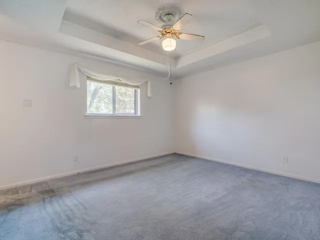 an empty room with a window and a fan