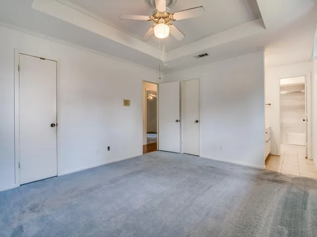 an empty room with closet and a chandelier fan