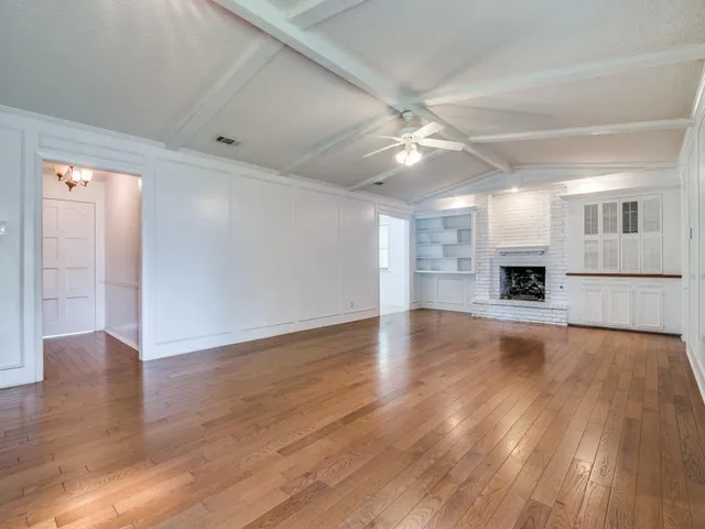 a view of a big room with wooden floor and a kitchen