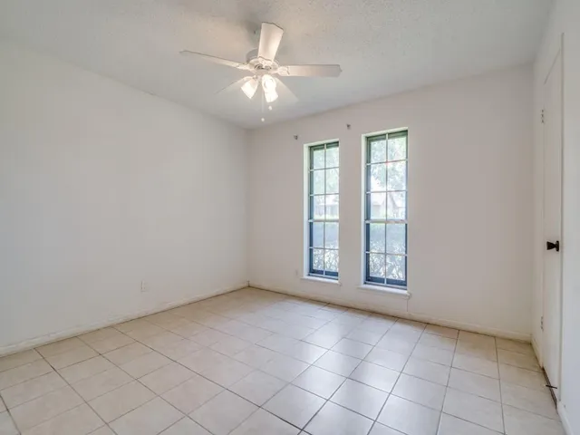 an empty room with windows and fan