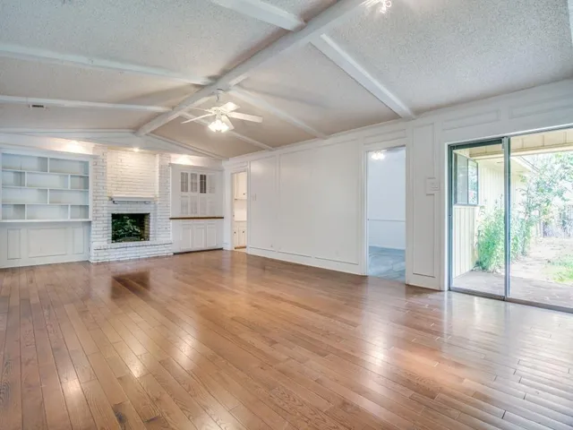 a view of a livingroom with a fireplace wooden floor and window