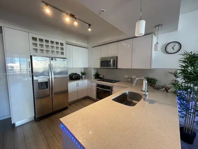 a kitchen with granite countertop a refrigerator a sink a counter space and cabinets