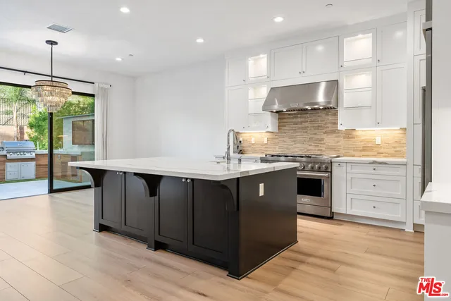 a view of a kitchen with kitchen island stainless steel appliances wooden floor dining table and a window
