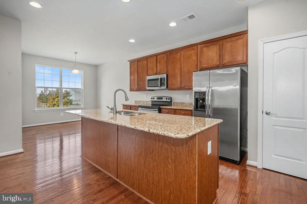 137 Silver Maple Road Middletown, DE 19709 - Photo 3 of 21 a kitchen with stainless steel appliances granite countertop a refrigerator a sink a stove a microwave and island with wooden floor