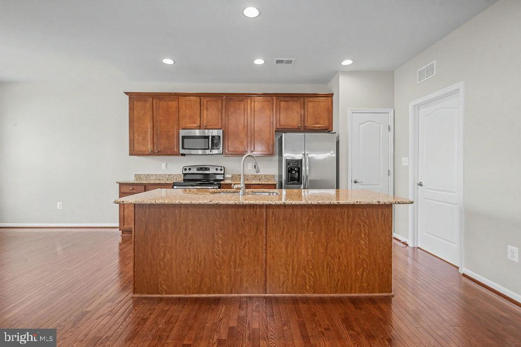 137 Silver Maple Road Middletown, DE 19709 - Photo 4 of 21 a kitchen with stainless steel appliances granite countertop a refrigerator a sink a stove a microwave and wooden floors